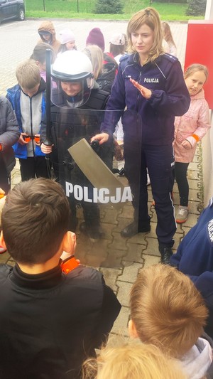 policjantka z dziećmi podczas przymierzania elementów wyposażenia policjantów